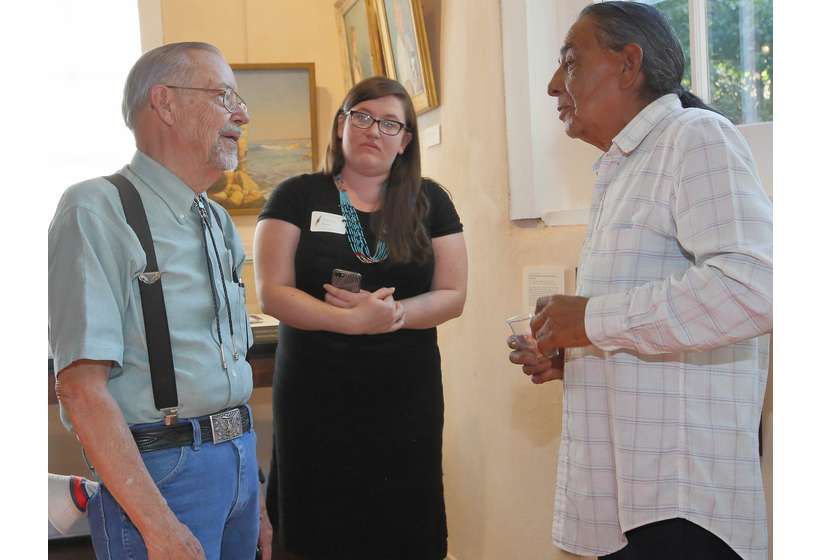 Texas patron Phil Woodard, University of Oklahoma intern Chelsea Herr, and Taos Pueblo resident Fred Lujan, Jr. discuss the Sharp exhibition.