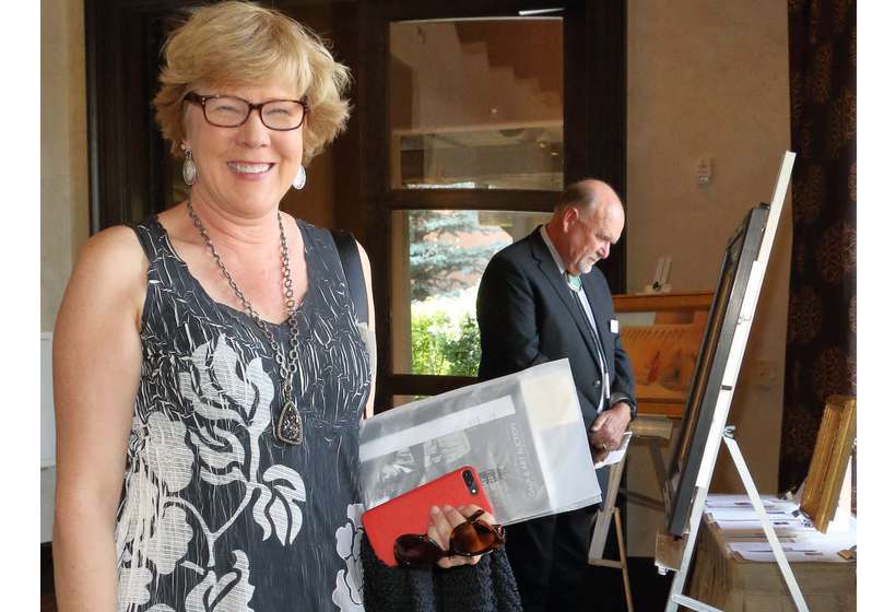 Patron Hallie Marcotte, with Board Chairman and Vice President Rich Rinehart in background, peruses the 2017 silent auction. Rich is now president of the Foundation.