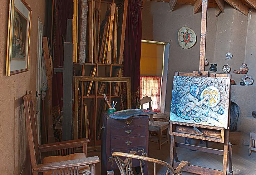Corner of Couse studio with incomplete painting, brushes, easel, and frames.